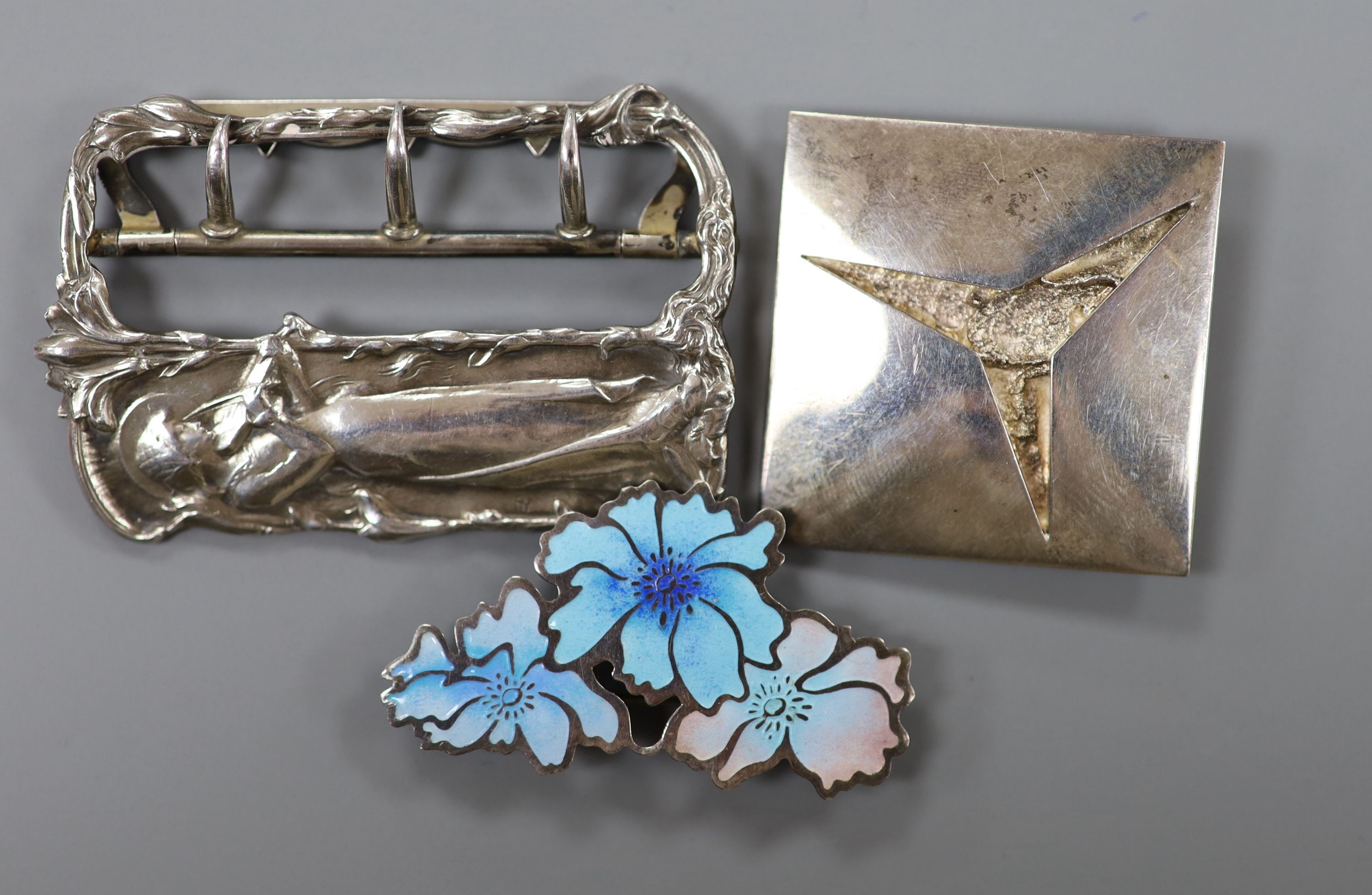 A French Art Nouveau style white metal buckle, a pair of 14k yellow metal and cultured pearl cluster set ear clips, a sterling and enamel brooch and one other silver brooch.